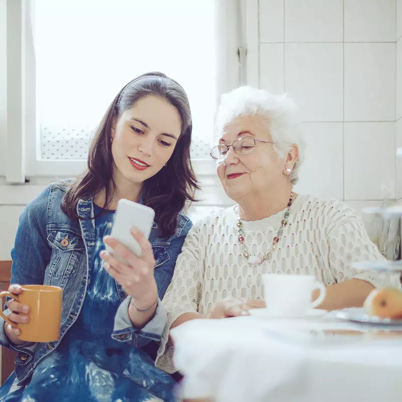A young woman with an older women checking a cell phone