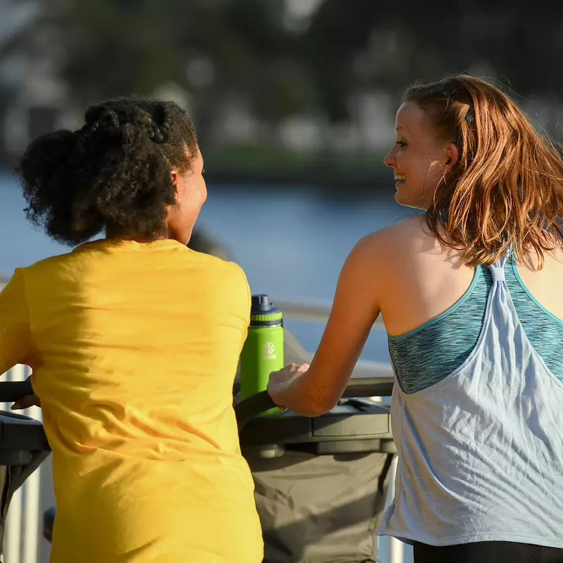 Friends exercising with their babies' strollers in the lakeside.