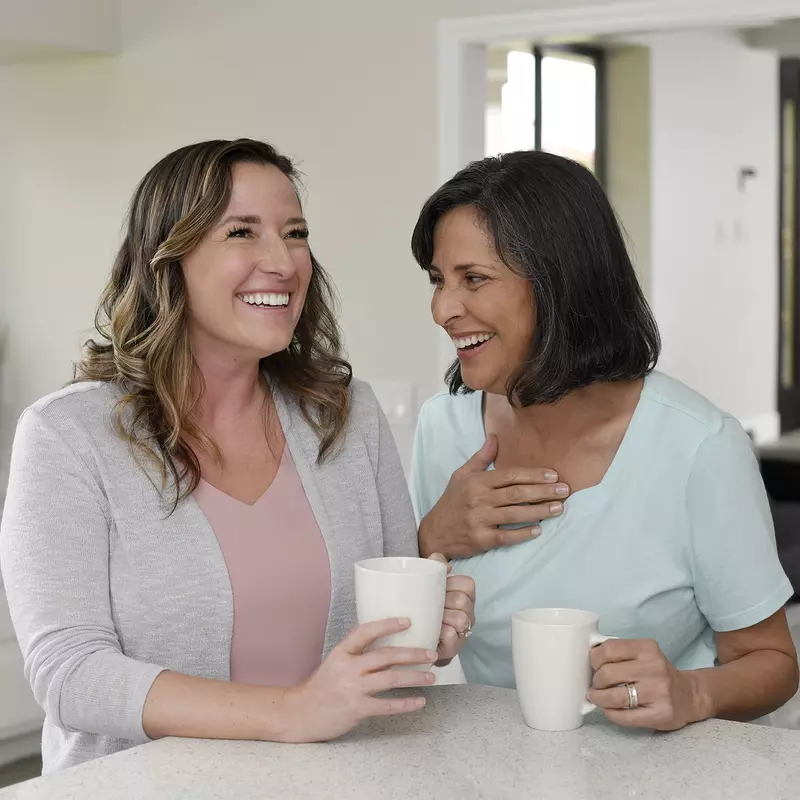 Two women laughing while having coffee together