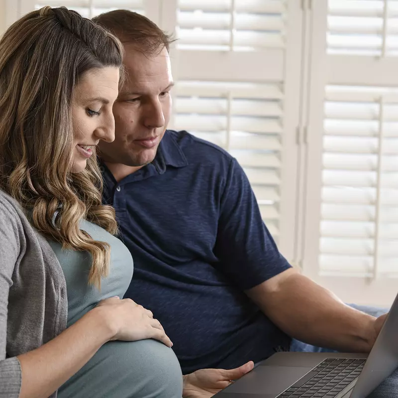 Pregnant woman and her husband looking at a laptop