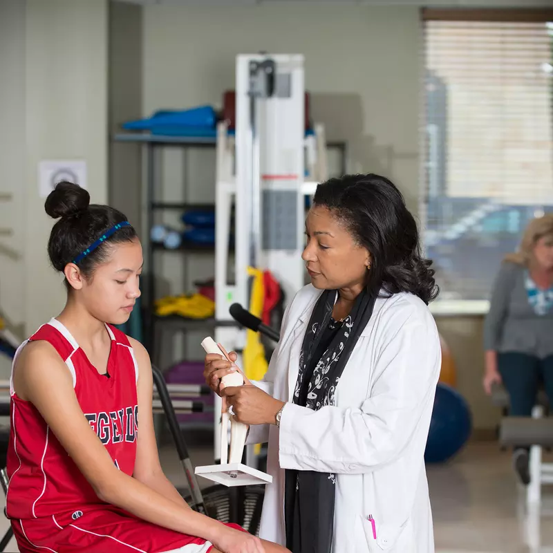 An young, injured basketball player is seen by her doctor