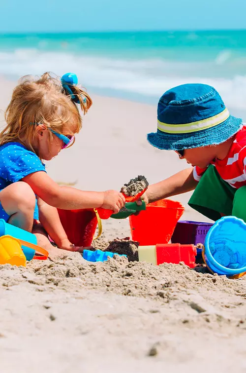 A young boy and girl building a sand castle on a beach.