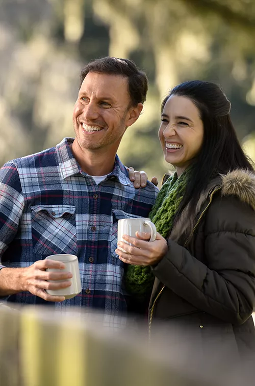 A couple holding mugs while outdoors in the winter.