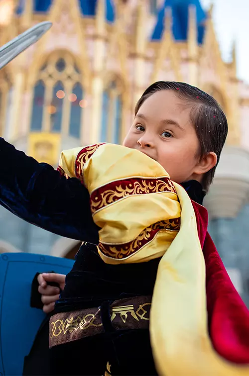 A boy dressed as a prince by Cinderella's castle at Magic Kingdom at Walt Disney World® Resort.