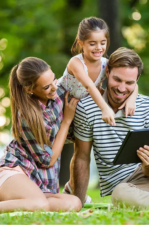 Happy family in park reading a tablet 