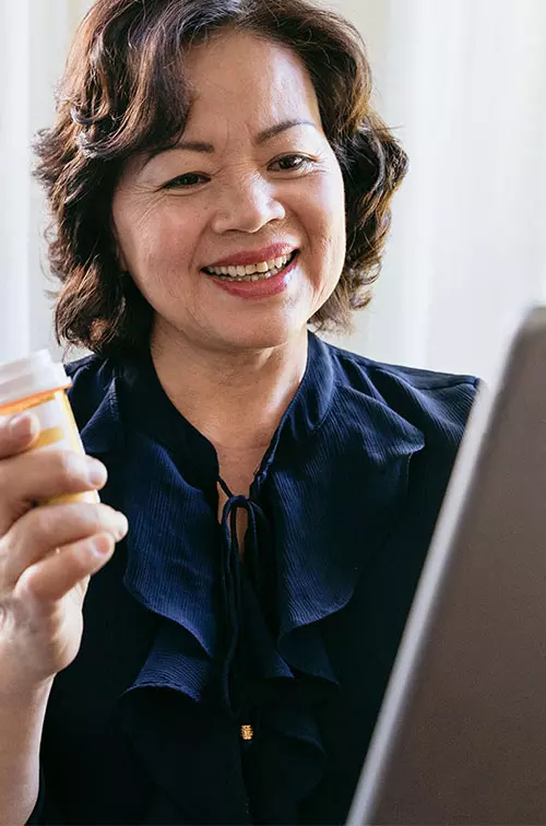 A woman holding a tablet and talking to her doctor about her prescription on a video call.