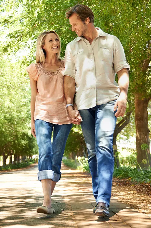 Adult couple walking in park lined by trees