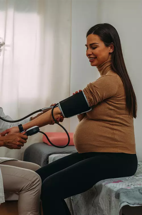 Pregnant woman getting her blood pressure checked by a physician.