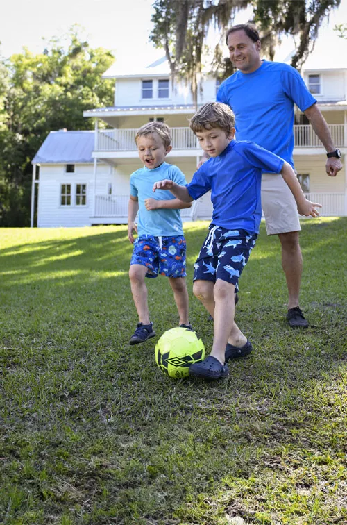 A father playing soccer with his children.