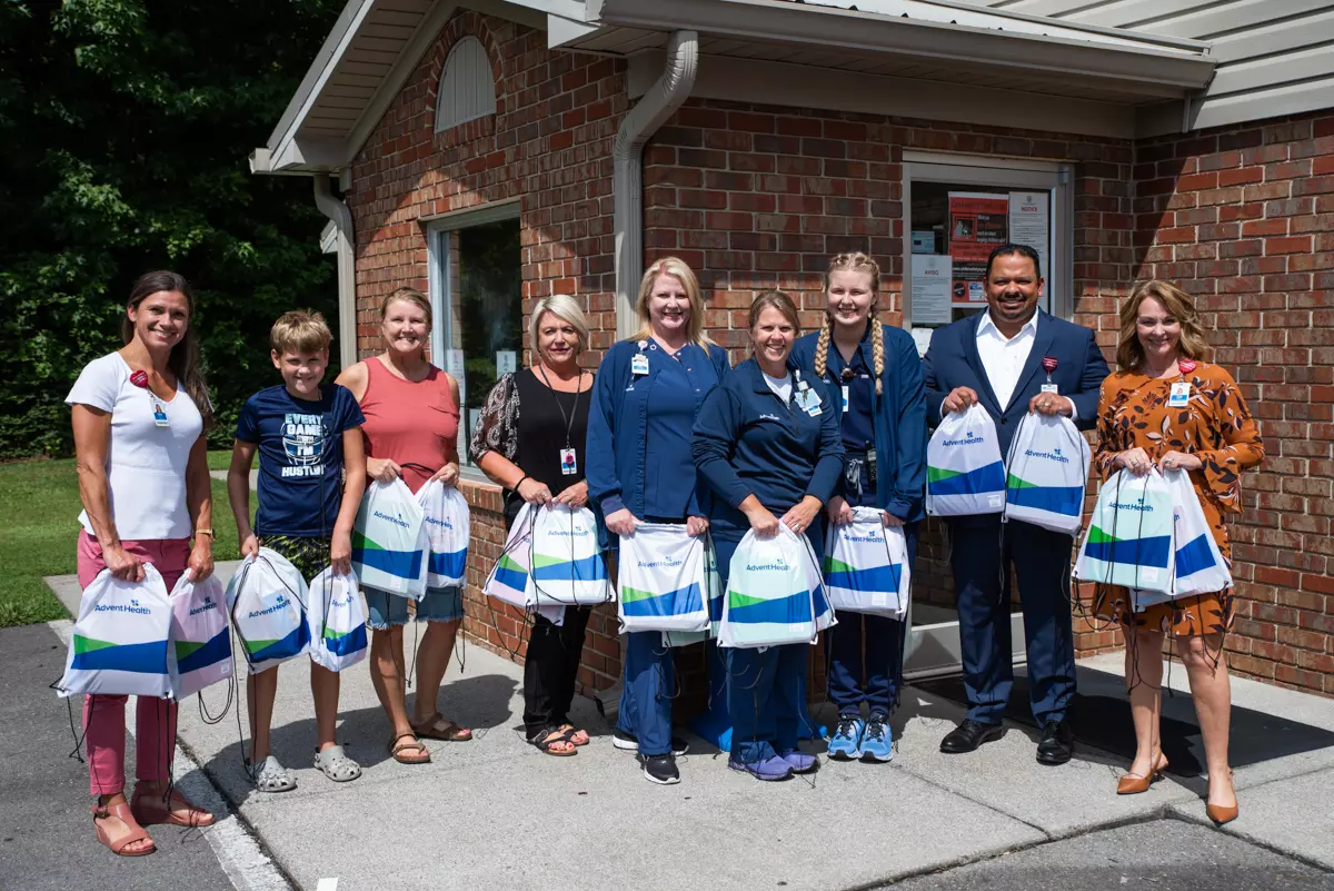 AdventHealth Murray team stands holding backpacks with school supplies