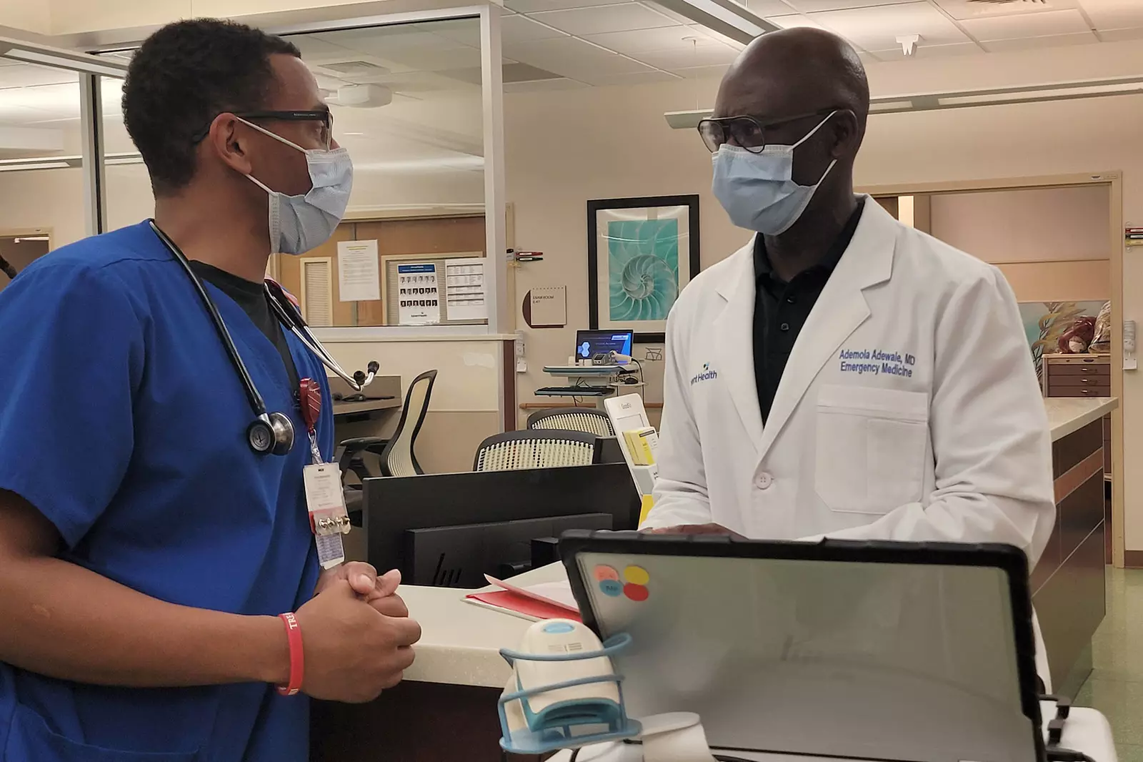 Ademola Adewale, MD, advises colleagues on best patient care at the East Orlando campus.