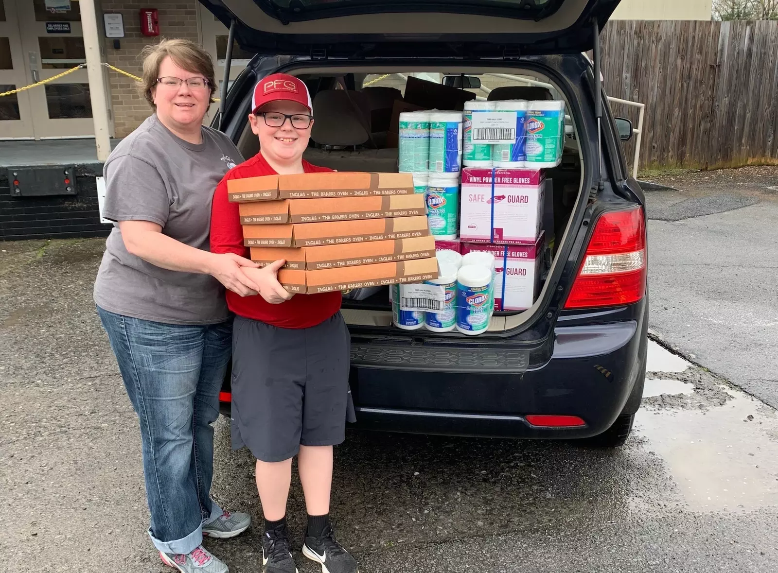 A woman and a boy with a trunk full of donations.