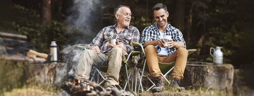 Two men sit in front of a fire and talk about their health