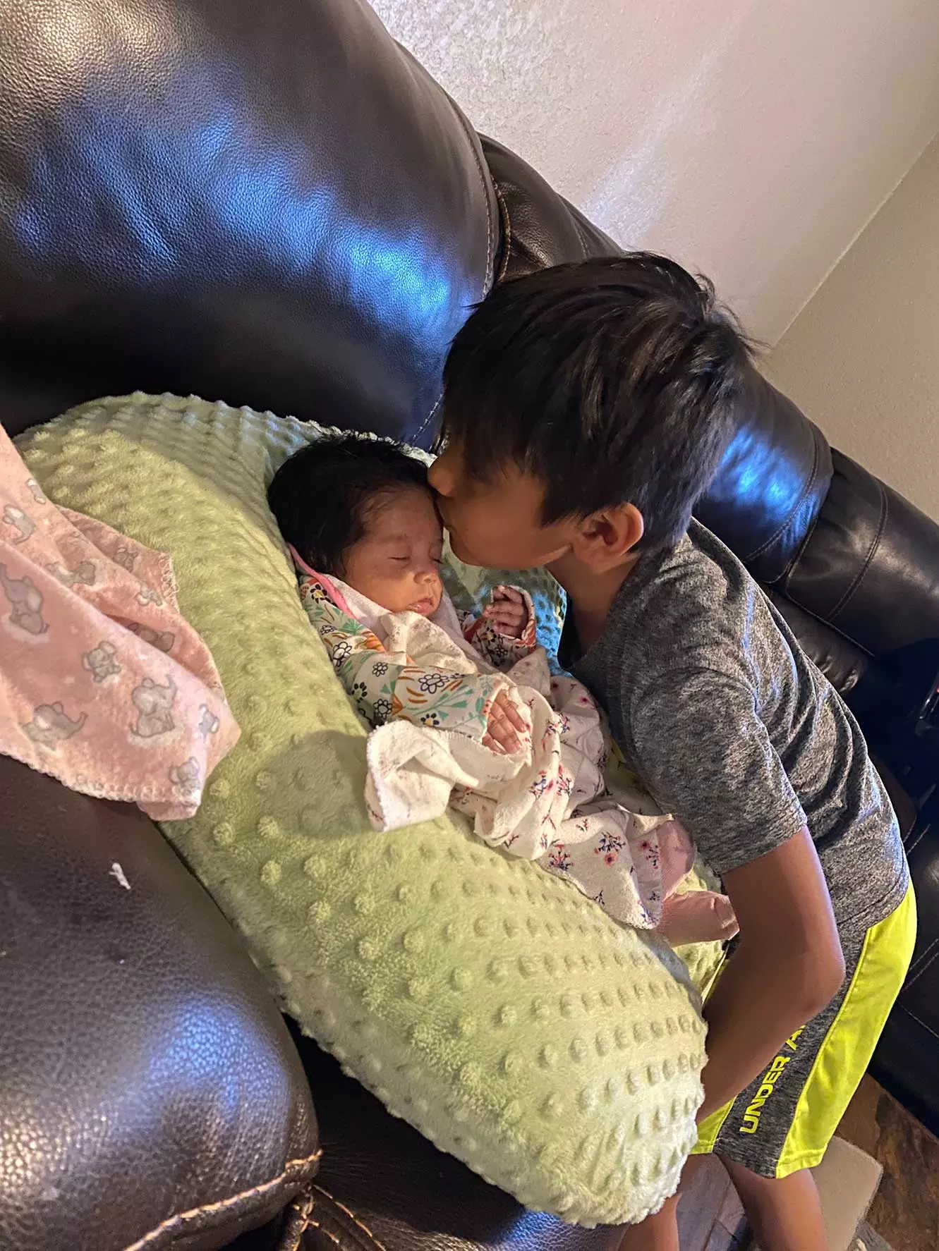 A brother kissing his baby sister