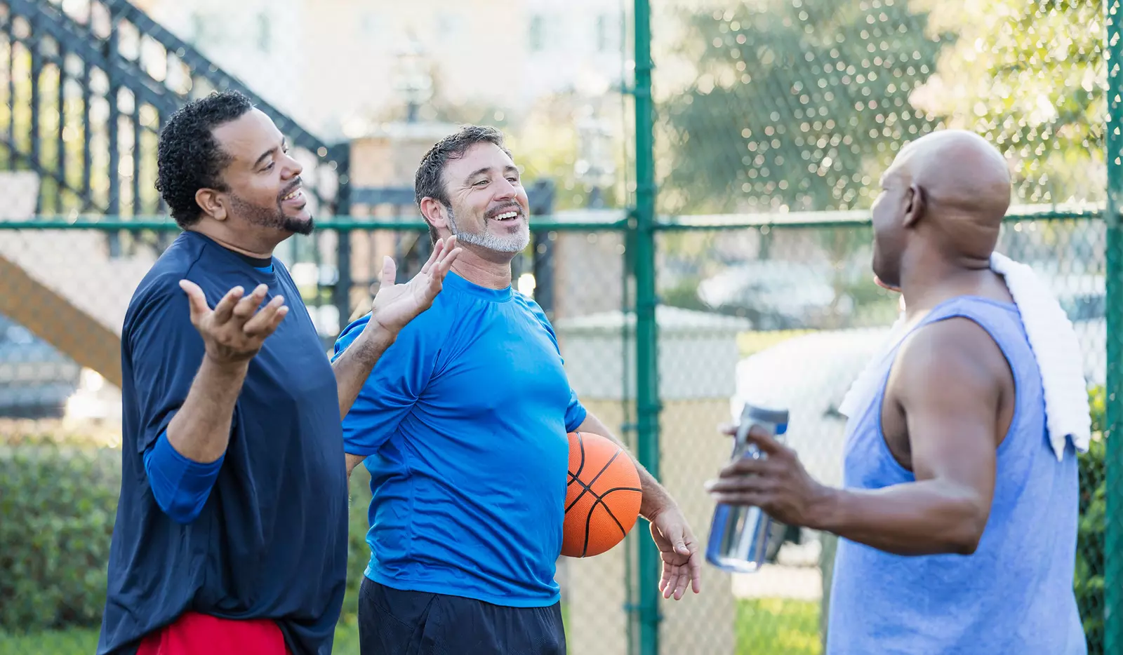 A group of older men talking and taking a break after a round of basketball