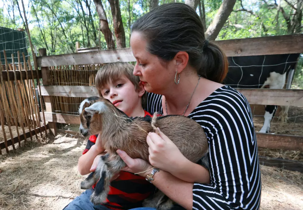 Cameron Munoz and one of her sons cuddle a baby goat at Puzzle Ranch, their nonprofit for children with autism.