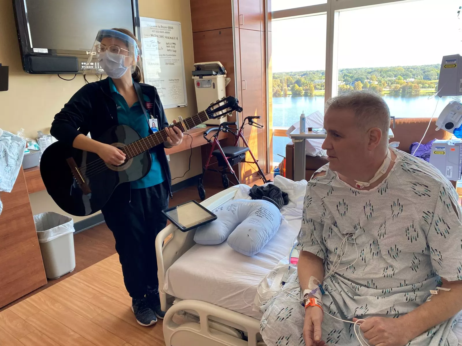 David Wilkinson, AdventHealth Orlando's first COVID lung transplant recipient, with music therapist Hannah Warner as she plays guitar.