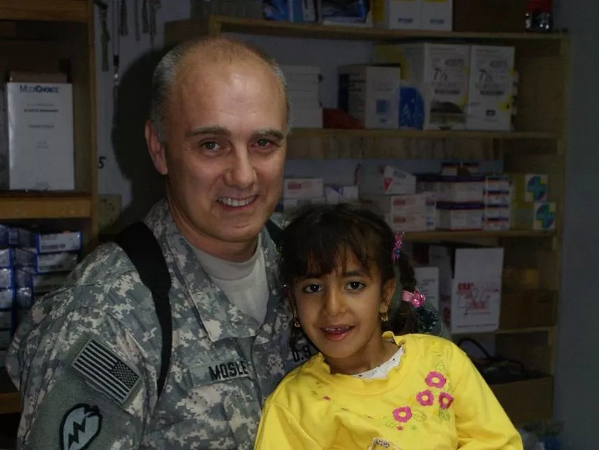 Dr. E. Wayne Mosley served seven tours in Afghanistan and Iraq as a combat physician with the U.S. Army. He's pictured here with a young patient in Mosul, Iraq. Photo Courtesy of Dr. E. Wayne Mosley