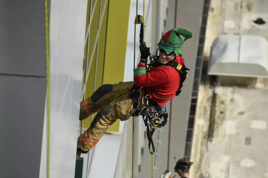 Elf in action rappels down the hospital building to greet pediatric patients at AdventHealth for Children.