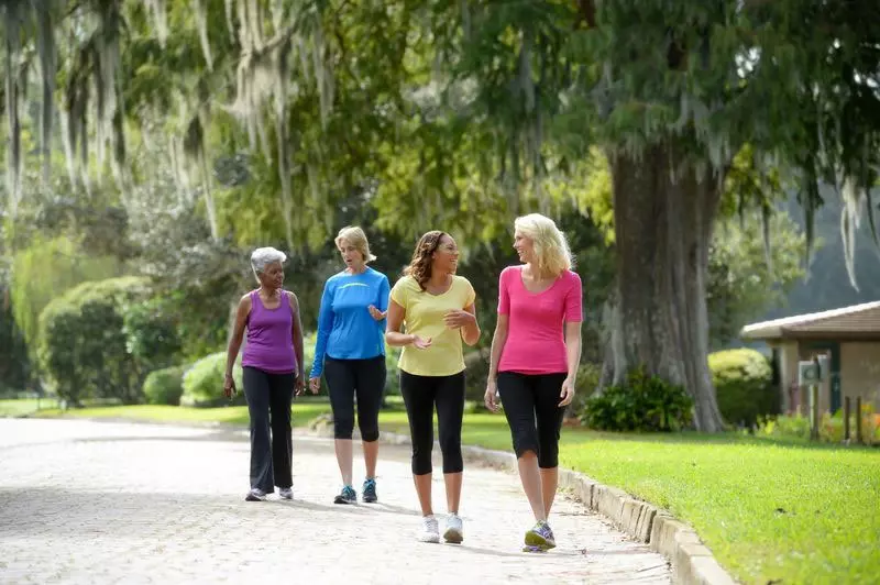 A group of mature ladies walking outdoors while chit-chatting