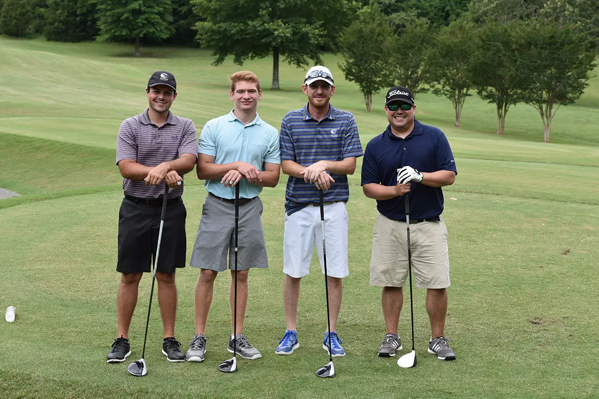 Group of golfers standing with golf clubs in hand.