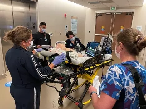 A care team running a simulation with a mannequin on a stretcher