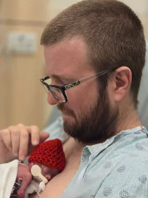 Greg Peele holds his infant daughter, Charlotte, skin to skin against his chest.