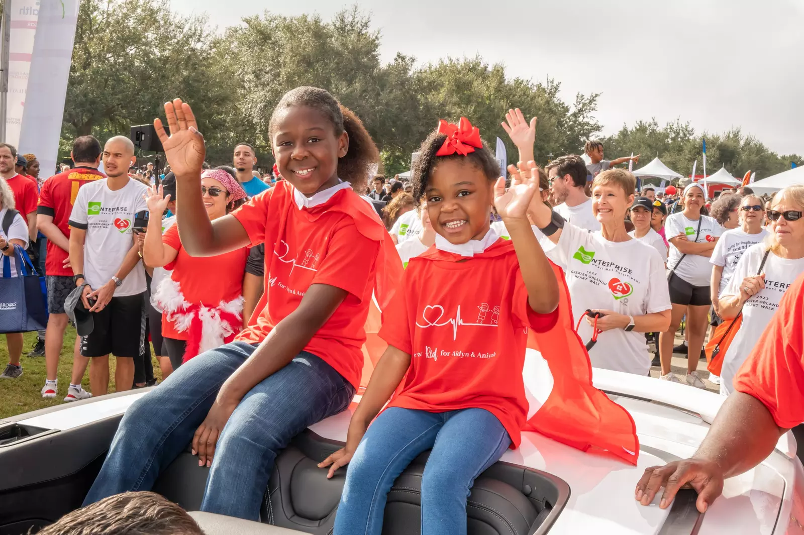 Aidyn, 8, and Aniyah, 4, ride in a parade at the American Heart Association's 2022 Greater Orlando Heart Walk held at UCF.