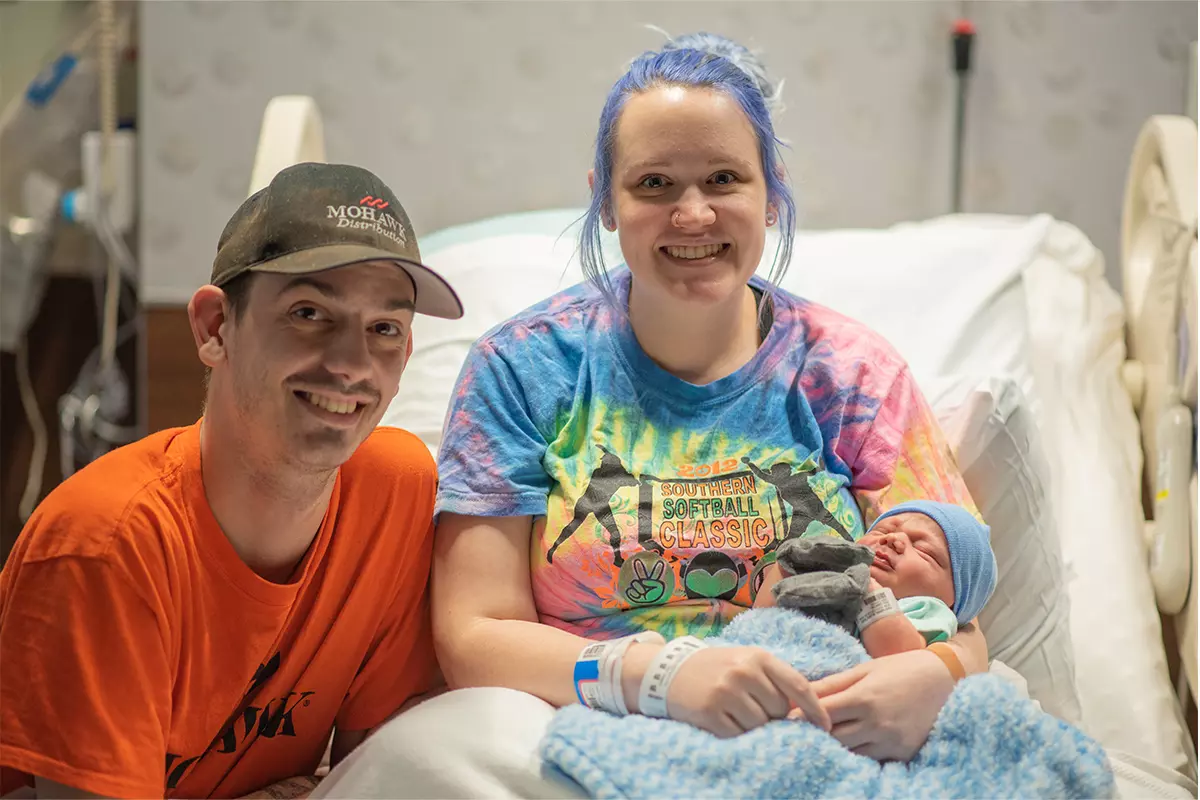 A couple at a hospital's bed with their new born baby.