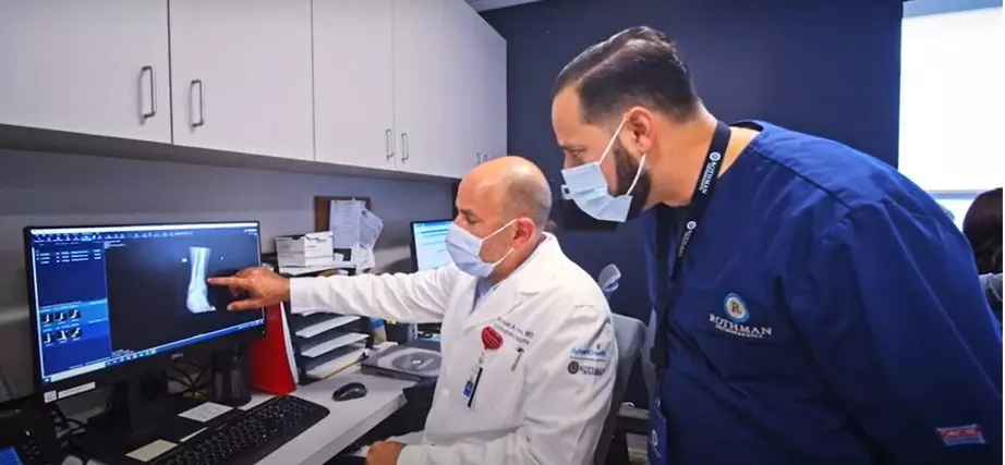 Dr. Michael Hawks (seated), orthopedic trauma surgeon and medical director for AdventHealth and Rothman Orthopaedics in Central Florida, confers with a fellow physician.