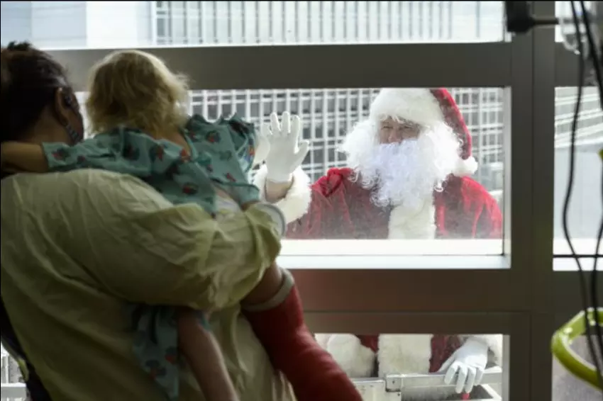 Santa Claus appears outside the sixth-floor window of AdventHealth for Children to greet a young patient.