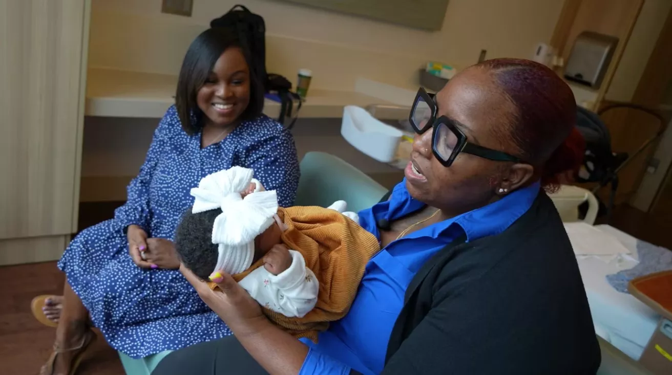 Care coordinator Erike King holds Eliza Gordon's baby girl Trinity.